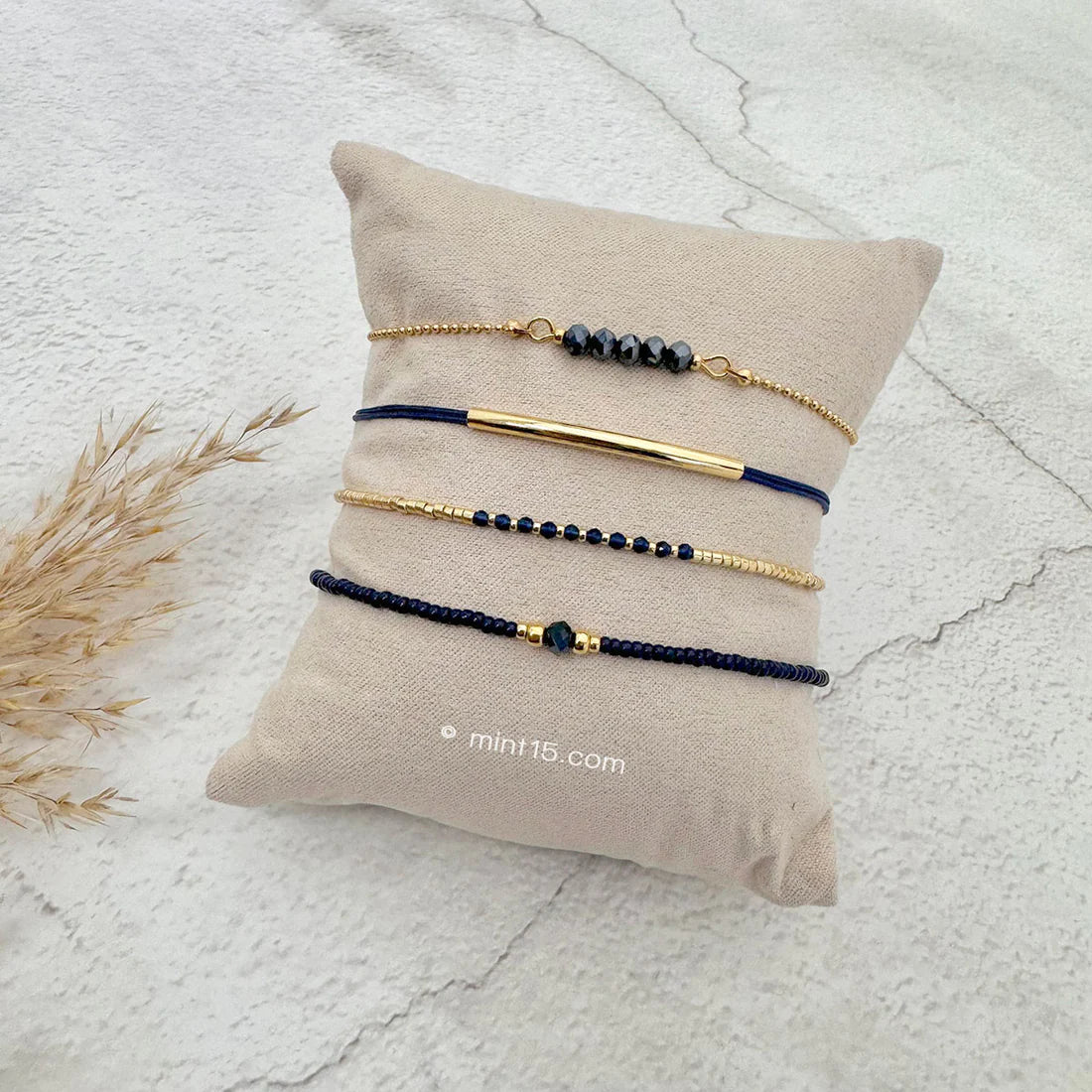 Armbanden set navy chic, goudkleurig, maat 16-19cm, op een sieradenkussentje in wit zand.